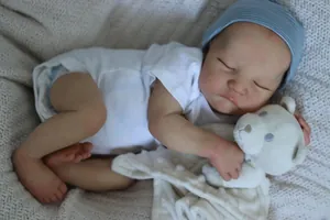 Close-up of lifelike newborn baby doll with 3D skin texture holding a small teddy bear