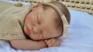 Close-up of 49cm reborn doll with 3D skin details, closed eyes, and lace headband