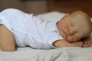 Close-up of lifelike 19 inch reborn baby doll with detailed 3D skin and white bodysuit