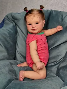 Close-up of lifelike reborn doll with brown pigtails in strawberry print romper