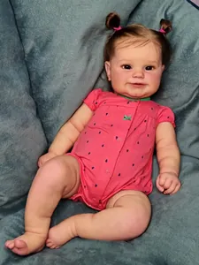 Detailed macro shot of Maddie reborn baby doll with pink hair buns and printed romper