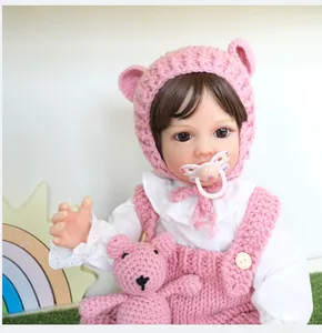 Detailed view of pink knitted doll outfit with bear ear hat and matching plush toy