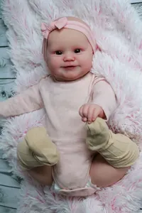 Dettaglio della bambola Maddie Reborn con vestito rosa su un morbido tappeto
