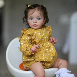 Realistic Missy reborn baby doll in yellow floral romper sitting in a white egg chair