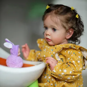 Realistic reborn baby doll Missy in yellow floral dress with purple plush bunny toy