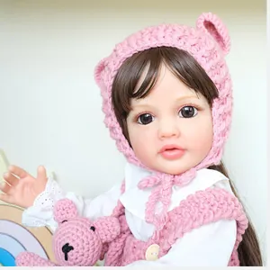 Lifelike 55cm baby doll wearing pink handmade crochet bear hat and overalls set