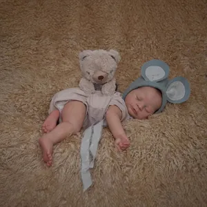 Realistic 49cm reborn baby doll with 3D skin texture, blue hat and plush bear toy