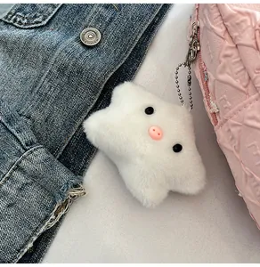 Gros plan du pendentif cochon en peluche blanche en forme d'étoile sur un sac rose matelassé