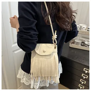 Detail of cream faux suede crossbody bag with long fringes and decorative knot strap