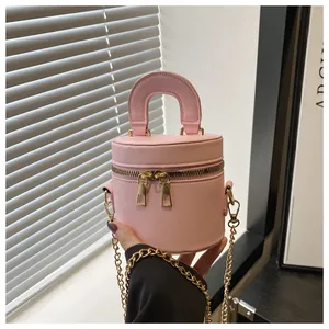 Détail du sac seau cylindrique rose avec double fermeture éclair dorée et texture en cuir PU