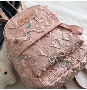 Gros plan sur le sac à dos rose matelassé avec broderie nœud et pendentif peluche