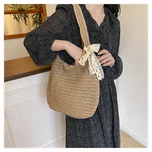 Close-up of handmade woven straw tote bag with delicate white lace bow detail