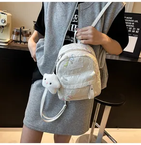 Détail du sac à dos matelassé blanc avec broderie papillon et pendentif en peluche