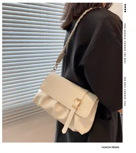 Détail d'un sac bandoulière crème avec plis froncés et bandoulière tissée chic