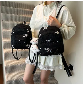 Détail du sac à dos noir matelassé avec broderie de nœud et breloque cochon en peluche