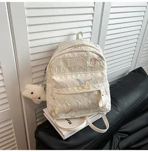 Détail du sac à dos blanc matelassé avec broderie colorée et pendentif nuage doux