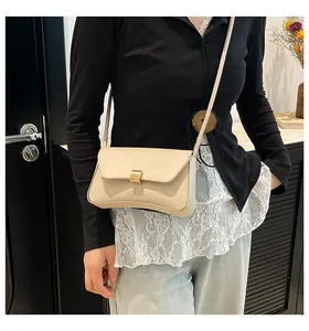 Detail view of a cream vintage baguette bag with a gold buckle worn by a model