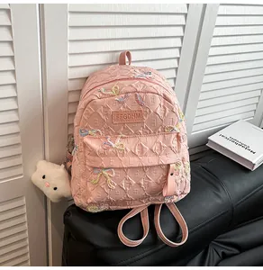 Vue détaillée du sac à dos matelassé rose clair avec nœuds colorés et breloque en peluche