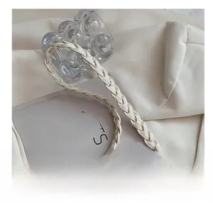 Détail de la poignée en cuir tressé crème et crochet en métal doré sur le sac à main