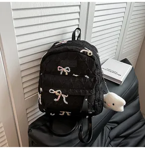 Détail du sac à dos matelassé noir avec broderies papillons colorées et breloque nuage