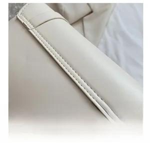 Détail macro des coutures de précision sur un sac à main en cuir de couleur crème