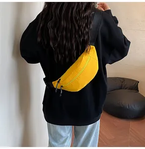 Detailed view of the bright yellow nylon crescent crossbody bag worn by a model