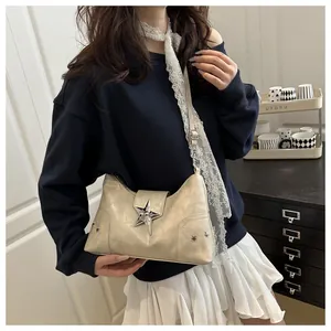 Dettaglio di una borsa sottobraccio punk beige con una grande fibbia a stella argento