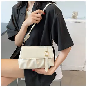 Sac à bandoulière plissé crème chic avec bandoulière tressée et boucle dorée sur modèle