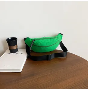 Detail of bright green crossbody sports bag with black strap on a wooden desk