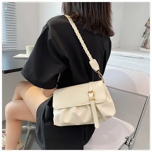 Détail d'un sac bandoulière plissé crème avec sangle tissée et boucle en métal doré