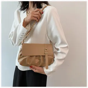 Détail d'un sac à main plissé marron clair avec boucle dorée et bandoulière tressée