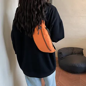 Vibrant orange crescent crossbody bag with adjustable strap worn over a black hoodie