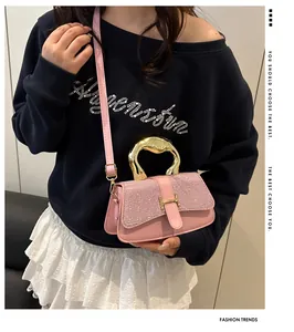 Detail of pink crossbody bag featuring sparkling texture and golden H buckle on model