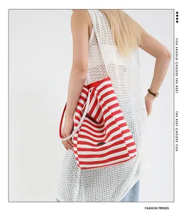 Détail du sac cabas en toile rayé rouge et blanc avec emblème sur le dos du mannequin