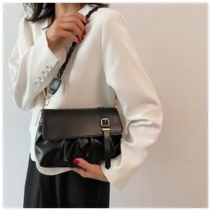 Détail du sac plissé en similicuir noir avec boucle dorée et bandoulière tressée