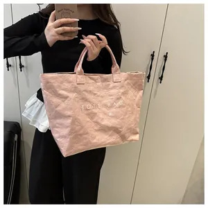 Close-up of pink Tyvek tote bag with white TOTE BAG lettering and crinkled texture