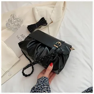 Détail du sac plissé noir avec poignée tressée et bandoulière réglable amovible