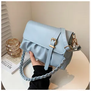 Détail d'un sac à main bleu clair plissé en PU avec anse tressée et boucle dorée