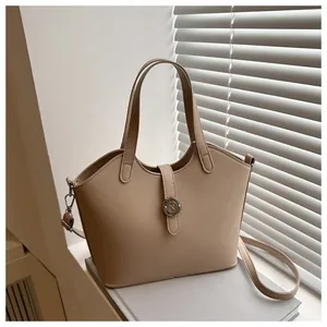Detailansicht beige Beuteltasche mit Metall-N-Logo auf minimalistischem Buchhintergrund