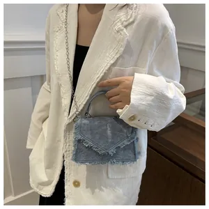 Λεπτομέρεια γαλάζιας τσάντας denim με ξεφτισμένες άκρες και μεταλλική αλυσίδα ώμου