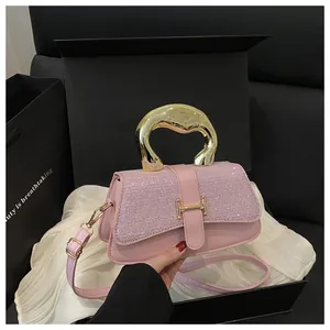 Detail of pink leather handbag with glittery flap and H logo on a luxury gift box