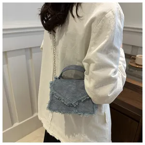 Λεπτομέρεια τσάντας denim με ξεφτισμένες άκρες και μεταλλική αλυσίδα ώμου