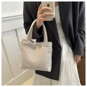 Close-up of cream textured woven tote bag with a golden button detail and elegant finish