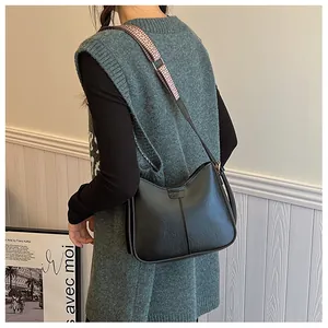 Detail view of black vintage underarm bag with dual straps worn by a model