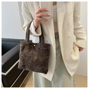 Detail of a brown woven texture handbag with a round gold buckle on a stylish model