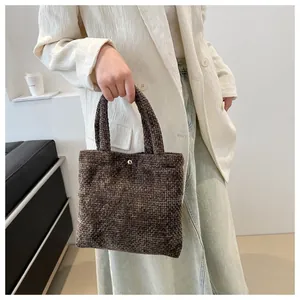 Detail of dark brown woven texture tote bag with gold metal buckle on white suit