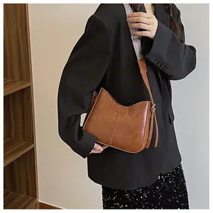 Close-up of brown vintage bucket bag with a wide geometric patterned shoulder strap