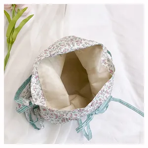 Detailed interior of floral canvas bucket bag showing beige lining and striped drawstring