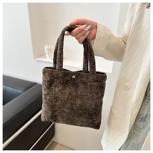 Detail of dark brown knit tote bag showing textured weave and gold metallic snap button