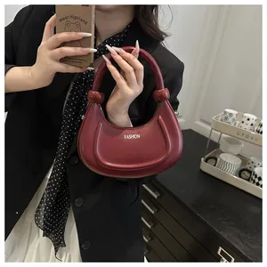 Nahaufnahme einer dunkelroten Halbmond-Handtasche mit modischer Aufschrift und Dekor